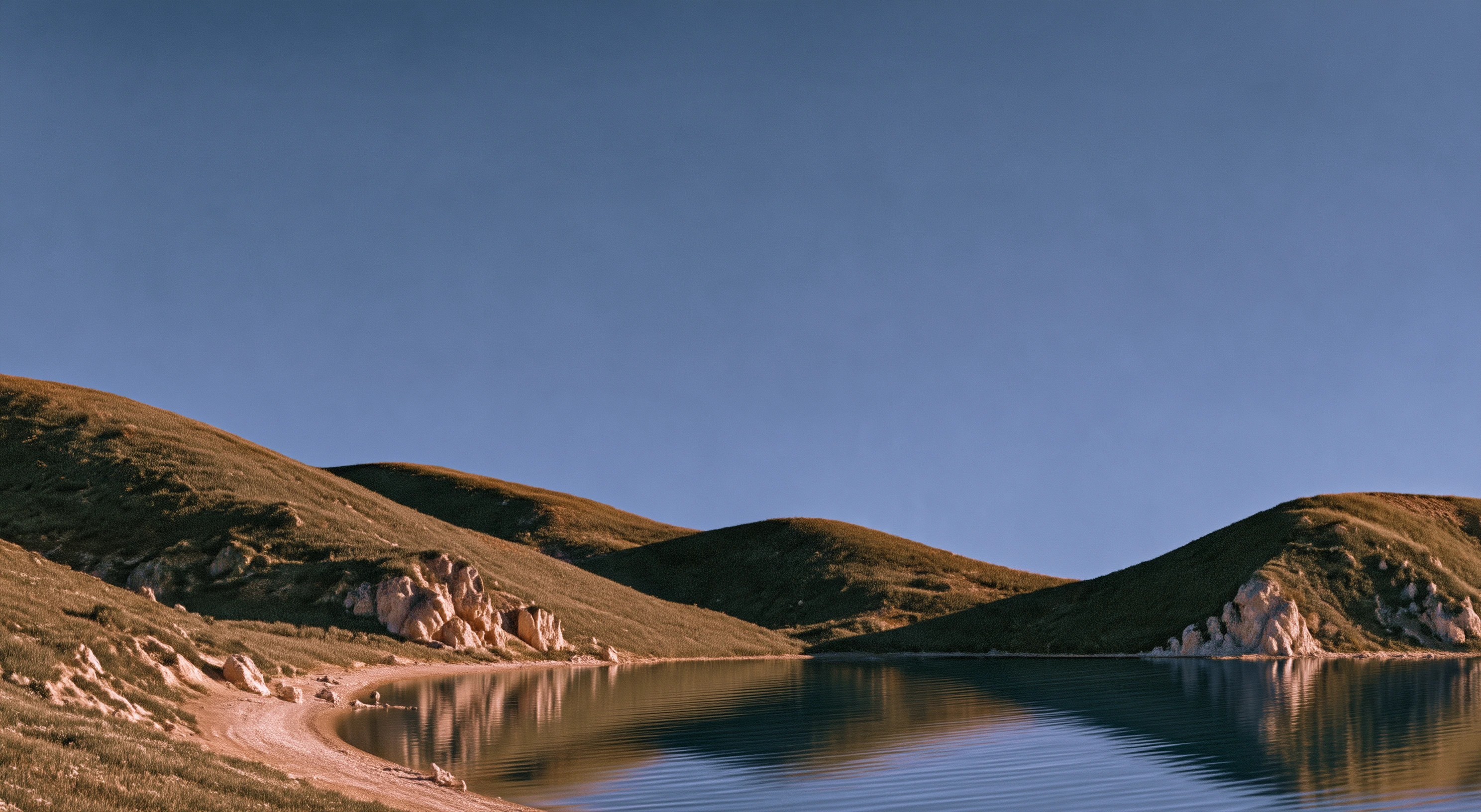 Quiet lake surrounded by low grassy hills